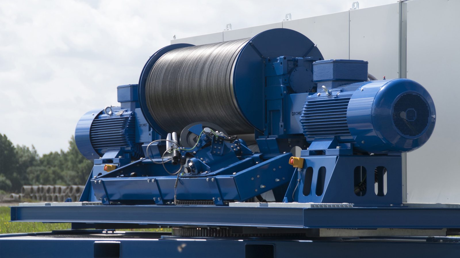 The drum and twin drive motors of a tethered-wing ground station, wound with steel tether and mounted on a container skid in open country
