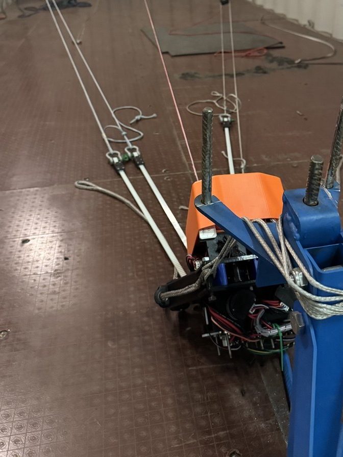 A test rig inside a container, with tensioned steel lines running back to an actuator