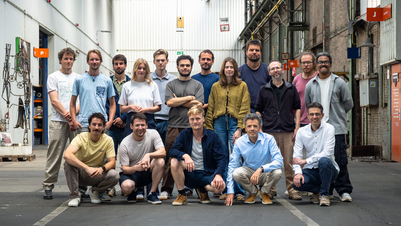 The team standing together in the aisle of the industrial hall the workshop is in