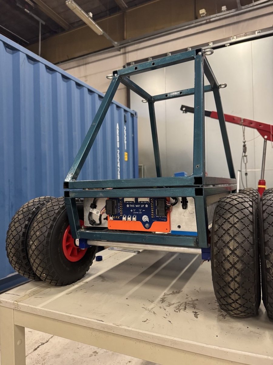 A welded steel frame on large pneumatic wheels, standing on a workbench mid-build